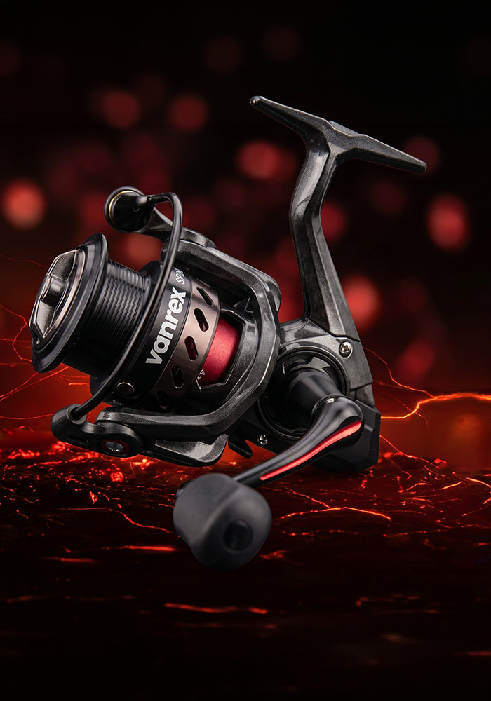 A black Vortex spinning fishing reel with red accents and a black handle, shown floating against a dark background with red bokeh lights and fiery embers.