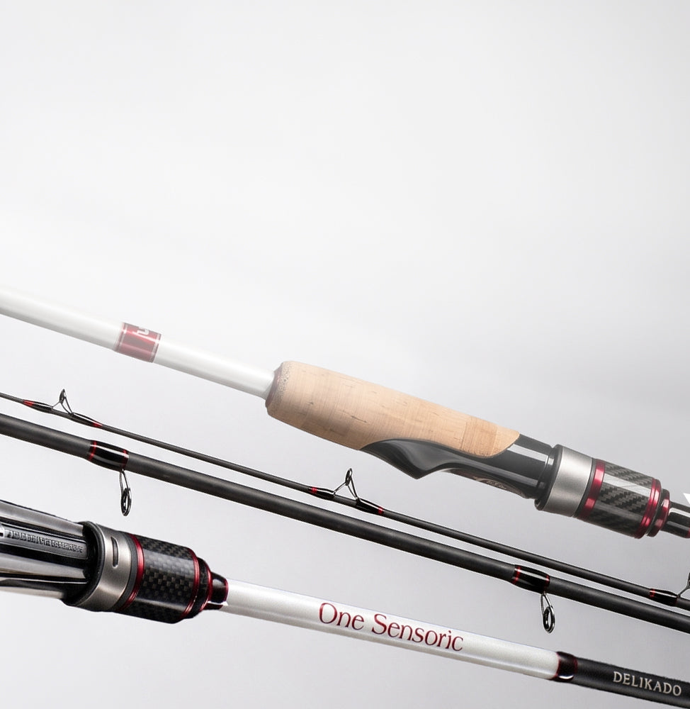 Close-up of fishing rods with white and black shafts, a light wood handle grip, and metallic reel seats on a plain light gray background.