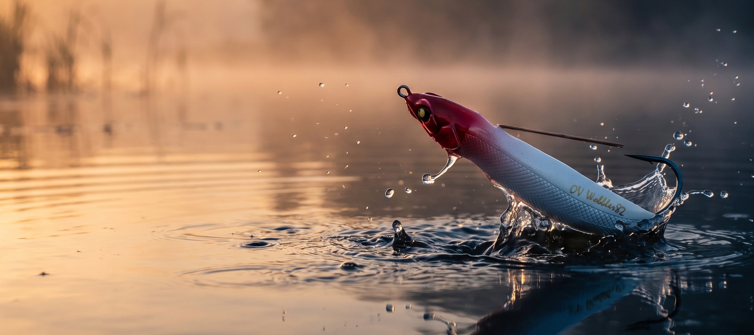 A red and white fishing lure splashes through water at sunrise, with misty reflections and ripples on the surface.