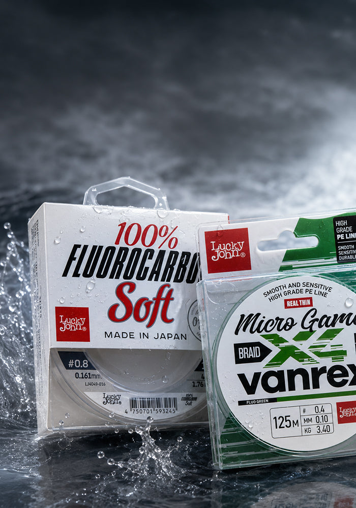 Two packages of Lucky Jolly fishing line displayed on a dark, wet surface with water droplets. The left package contains Lucky Jolly Soft fluorocarbon line, and the right package contains Lucky Jolly Vanrex braided line.