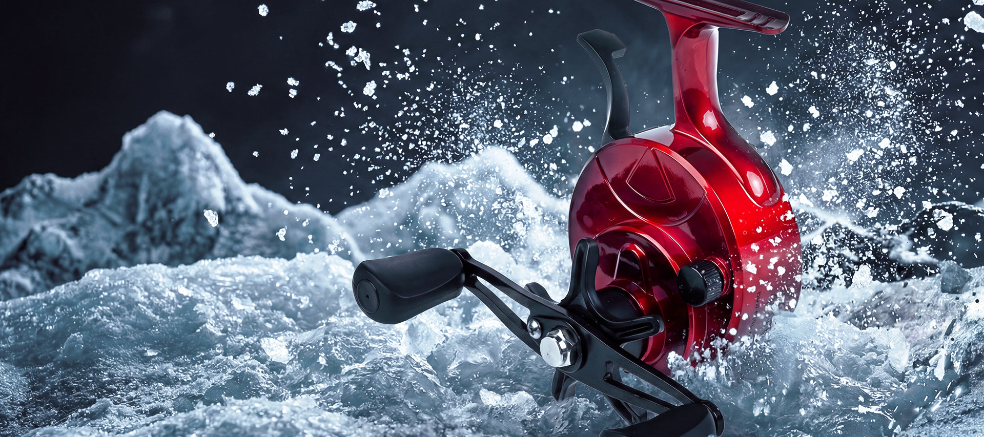 A red spinning fishing reel with a black handle is shown emerging from splashing icy water against a dark, dramatic background.