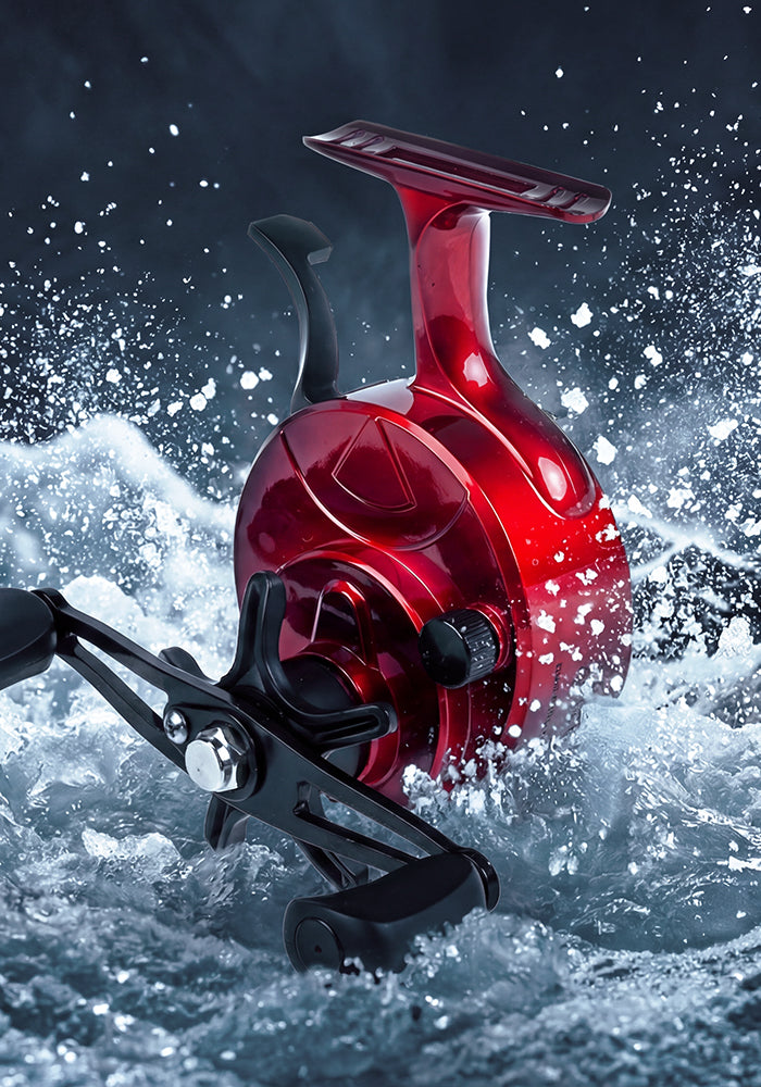 A glossy red spinning fishing reel with a black handle, emerging from splashing white water against a dark, dramatic background.