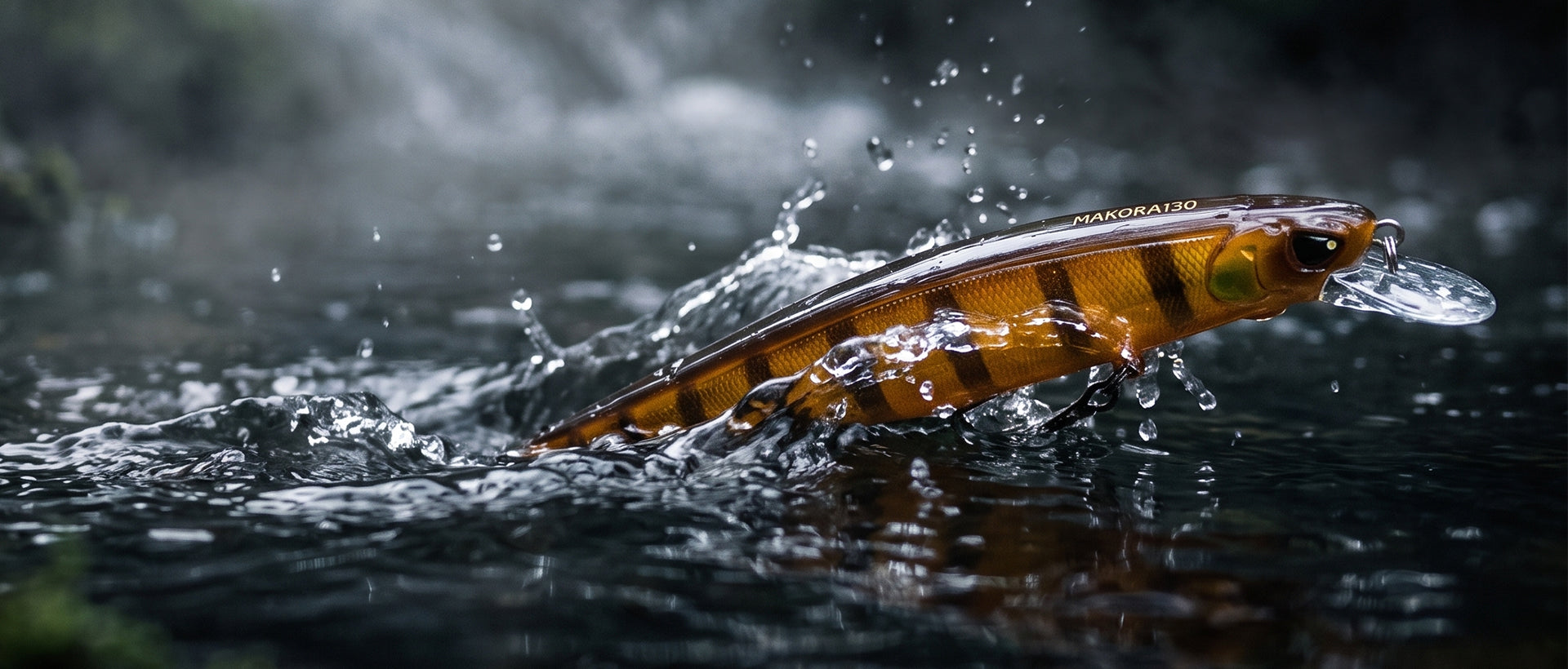 A realistic fishing lure shaped like a small striped fish jumping out of dark water, creating splashes. The lure has a metallic gold body with black and orange-brown stripes, and small white text near the top that reads 'REALISTIC'.
