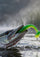 A close-up action shot of a green and yellow soft plastic snake lure being bitten by a fish in splashing water.